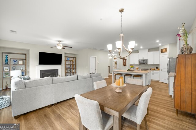 living room featuring wood-type flooring and ceiling fan with notable chandelier