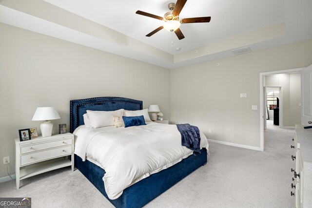 bedroom featuring a tray ceiling, carpet floors, and ceiling fan