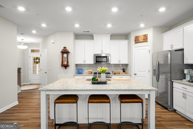 kitchen featuring stainless steel appliances, light stone countertops, a center island, and white cabinets