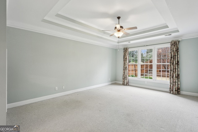 spare room featuring a raised ceiling, crown molding, carpet floors, and ceiling fan