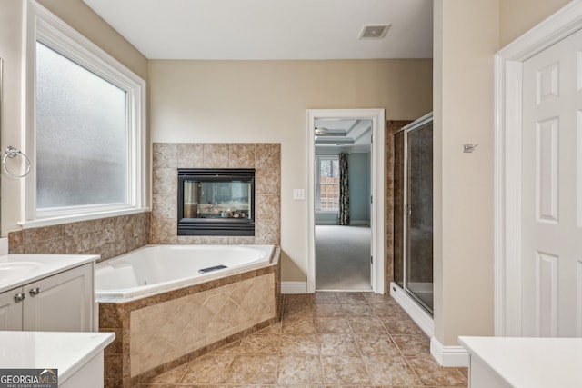 bathroom with a tiled fireplace, vanity, independent shower and bath, and tile patterned flooring