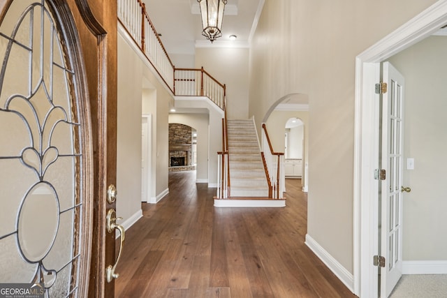 foyer featuring hardwood / wood-style flooring, a fireplace, ornamental molding, and a high ceiling