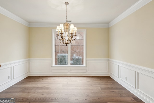 unfurnished dining area with an inviting chandelier, wood-type flooring, and ornamental molding