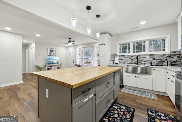 kitchen with a kitchen island, wood counters, sink, gray cabinetry, and white cabinets