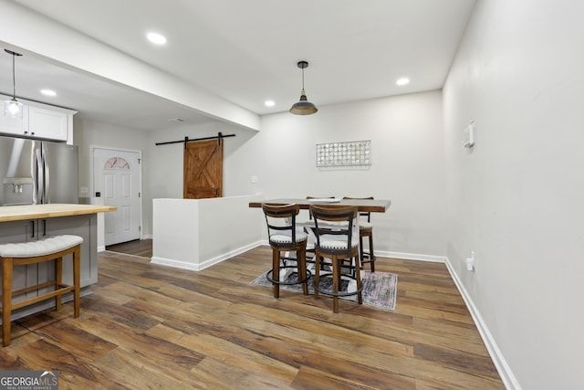 dining space with dark hardwood / wood-style floors and a barn door