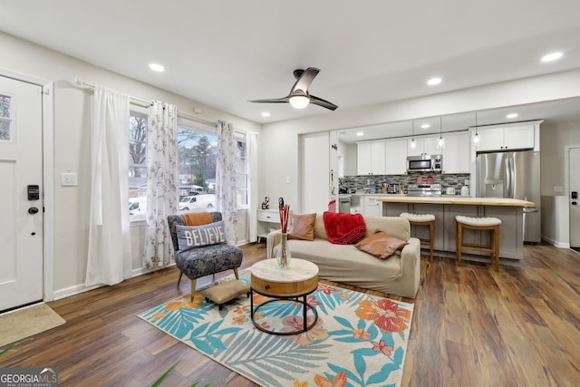 living room featuring ceiling fan and dark hardwood / wood-style floors