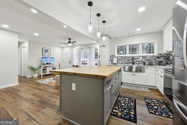 kitchen with sink, wooden counters, backsplash, white cabinets, and decorative light fixtures