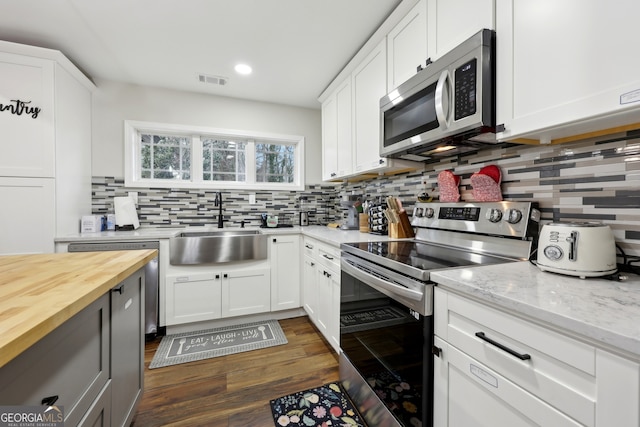 kitchen with sink, white cabinetry, tasteful backsplash, light stone counters, and appliances with stainless steel finishes