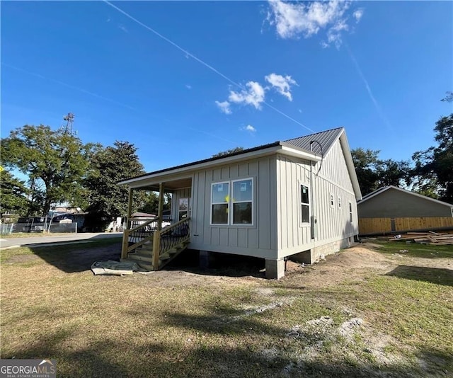 view of property exterior featuring metal roof, a yard, and board and batten siding