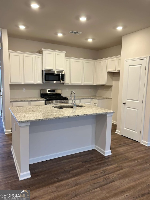 16 Wildflower Ln Unit 39, Dallas, GA 30132 - kitchen with stainless steel appliances, white cabinets, a center island with sink, dark wood-style floors, and light stone counters