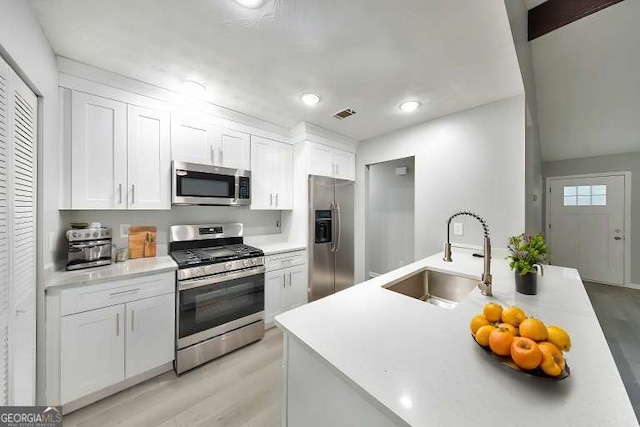 kitchen with sink, stainless steel appliances, light hardwood / wood-style floors, and white cabinets