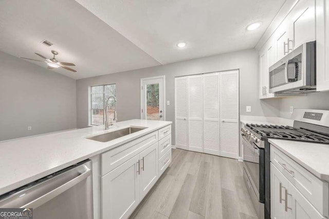 kitchen featuring sink, light wood-type flooring, white cabinets, and appliances with stainless steel finishes