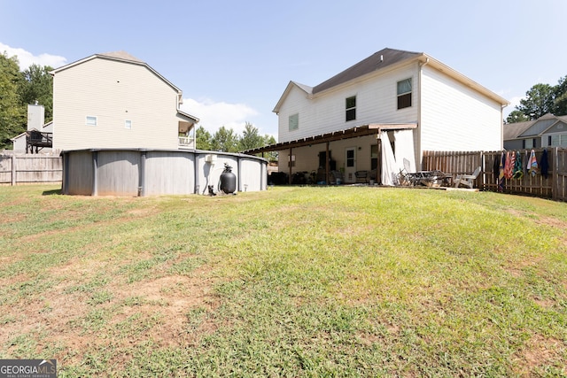 rear view of house featuring a swimming pool and a lawn