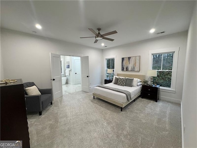 carpeted bedroom with ensuite bathroom and ceiling fan