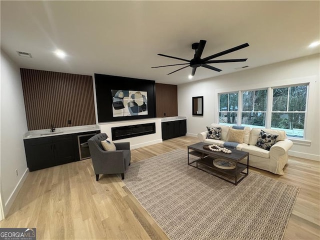 living room with sink, light hardwood / wood-style floors, and ceiling fan