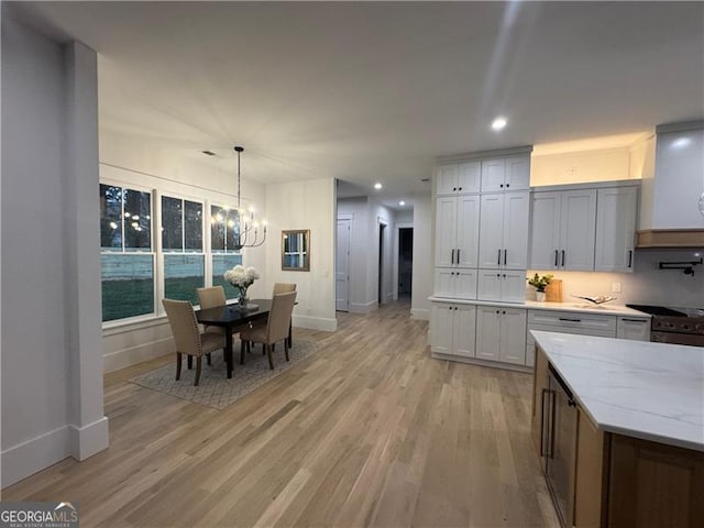 kitchen featuring light hardwood / wood-style flooring, white cabinetry, hanging light fixtures, a notable chandelier, and light stone countertops