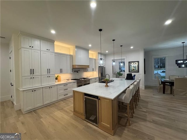 kitchen with white cabinetry, a spacious island, premium range hood, and beverage cooler