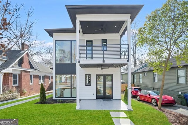 rear view of property with ceiling fan, a balcony, a patio, and a lawn