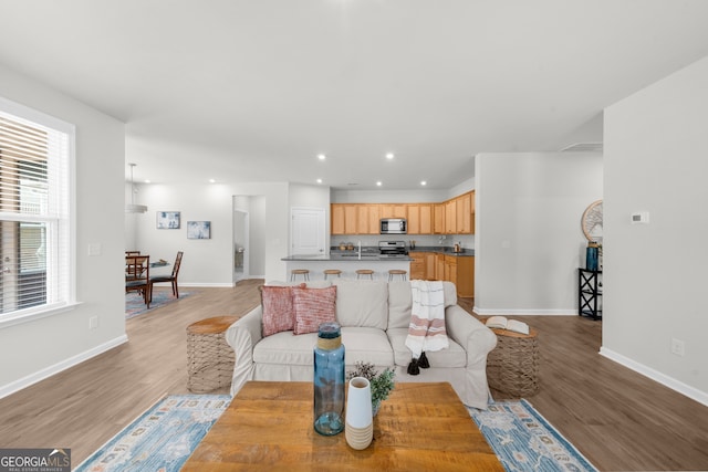 living area with light wood finished floors, baseboards, and recessed lighting