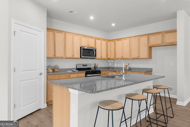 kitchen featuring stone counters, light brown cabinets, a sink, visible vents, and appliances with stainless steel finishes