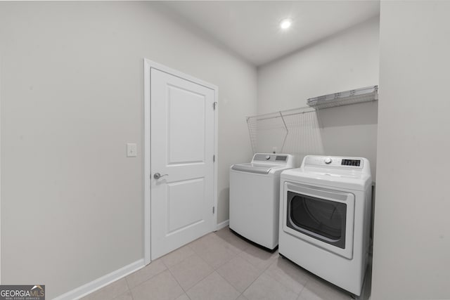 clothes washing area featuring laundry area, independent washer and dryer, baseboards, and light tile patterned floors