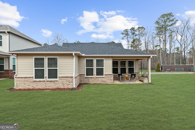 back of property with a patio, brick siding, a lawn, and a shingled roof