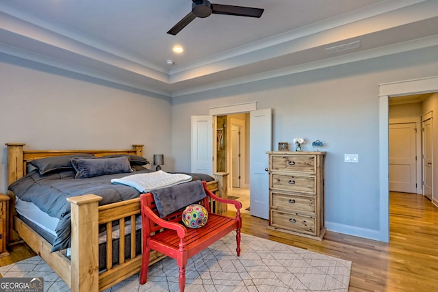 bedroom with a tray ceiling, light hardwood / wood-style floors, and ceiling fan