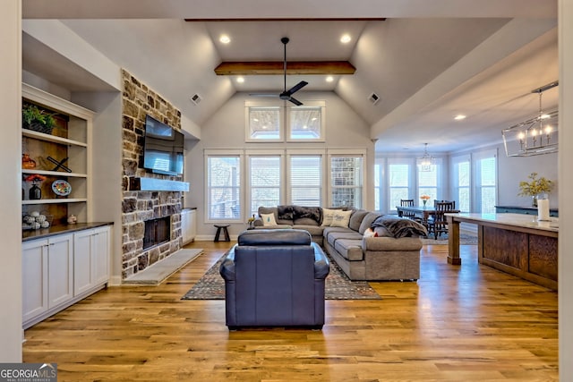 living room with beamed ceiling, a stone fireplace, high vaulted ceiling, and light hardwood / wood-style floors