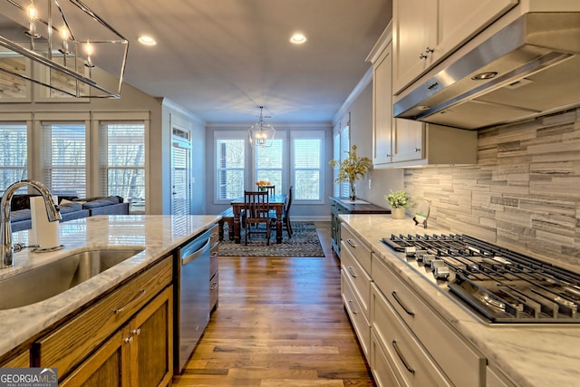 kitchen with white cabinets, stainless steel appliances, light stone countertops, and exhaust hood