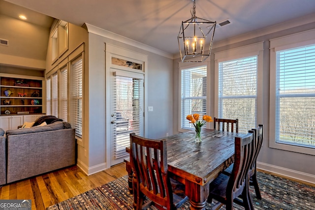 dining space featuring a notable chandelier, ornamental molding, light hardwood / wood-style floors, and a healthy amount of sunlight