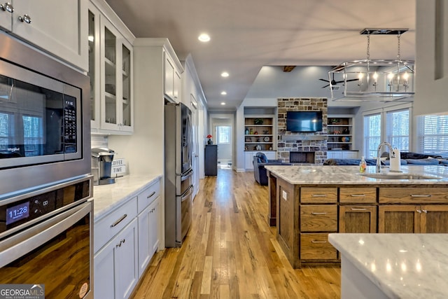 kitchen with white cabinetry, sink, light stone countertops, and appliances with stainless steel finishes