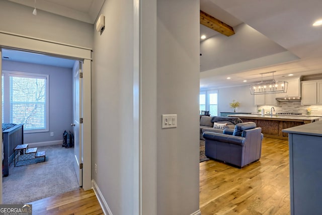 hallway featuring a raised ceiling and light wood-type flooring