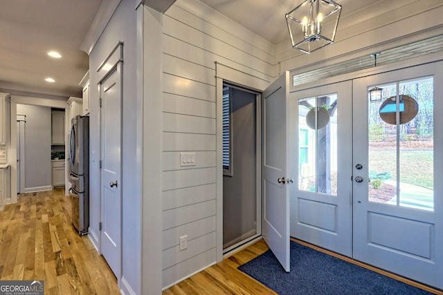 entrance foyer with french doors, wood walls, light hardwood / wood-style flooring, and a wealth of natural light