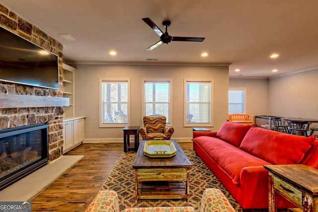 living room with crown molding, a fireplace, dark hardwood / wood-style floors, and ceiling fan