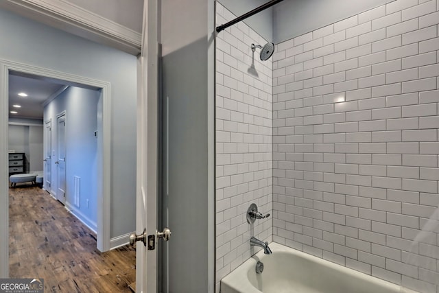 bathroom with crown molding, wood-type flooring, and tiled shower / bath