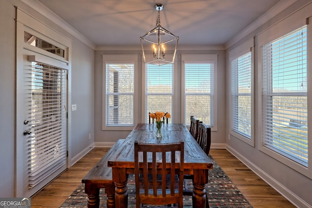 dining space featuring wood-type flooring, ornamental molding, and a notable chandelier