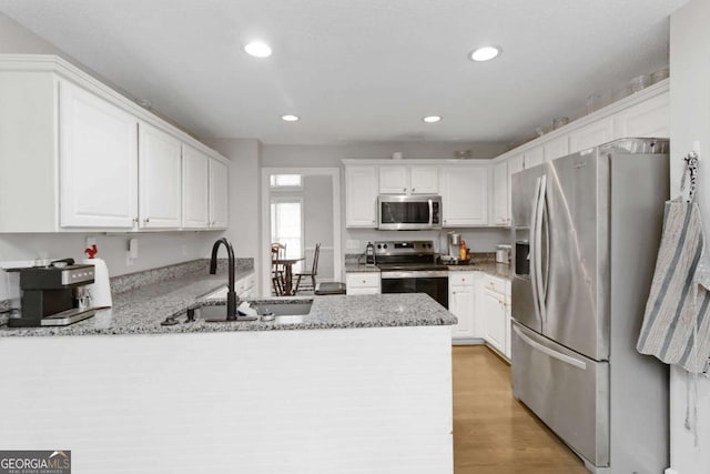 kitchen with white cabinetry, appliances with stainless steel finishes, kitchen peninsula, and sink