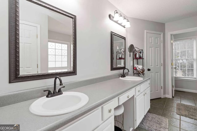 bathroom with tile patterned flooring, vanity, a wealth of natural light, and a textured ceiling