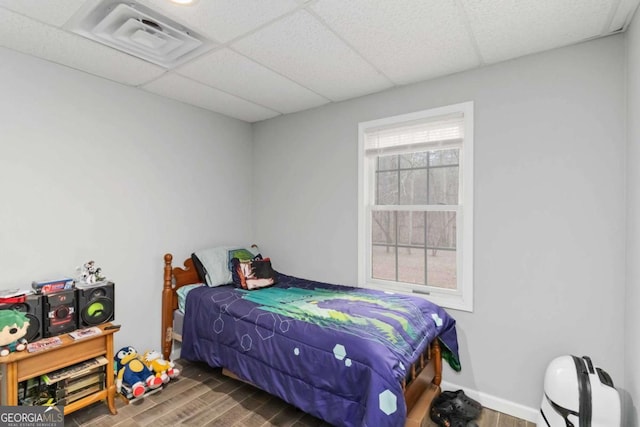 bedroom with dark wood-type flooring and a paneled ceiling