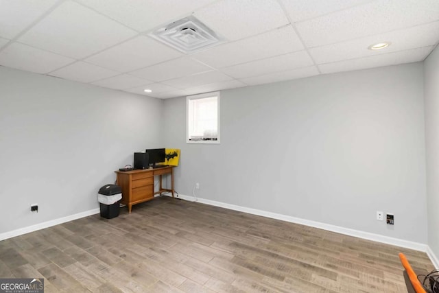 home office with dark wood-type flooring and a paneled ceiling