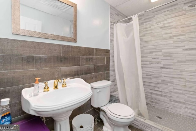 bathroom featuring tile walls, sink, toilet, and a shower with shower curtain