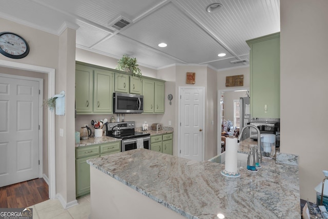 kitchen featuring green cabinets, stainless steel appliances, a peninsula, ornamental molding, and light stone counters