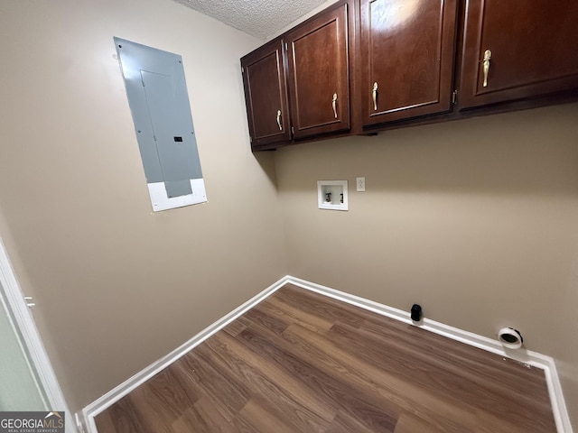 clothes washing area featuring electric panel, hookup for a washing machine, cabinet space, baseboards, and dark wood-style flooring