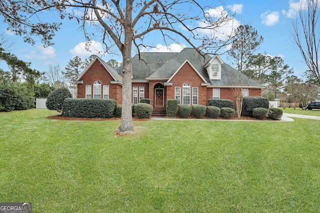 traditional-style house featuring brick siding, a front lawn, and roof with shingles