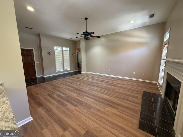 unfurnished living room with ceiling fan, a fireplace with flush hearth, wood finished floors, baseboards, and recessed lighting
