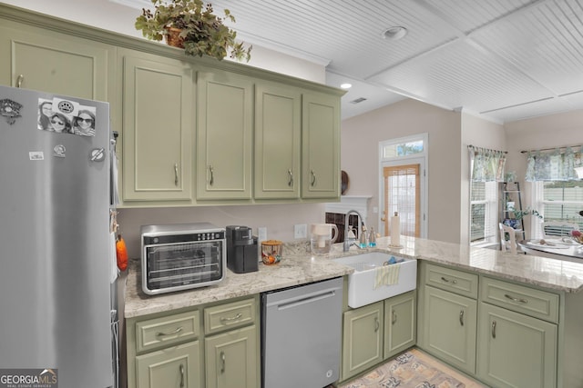 kitchen featuring green cabinetry, appliances with stainless steel finishes, a sink, and a peninsula