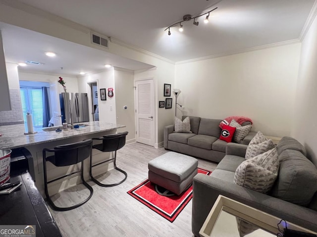 living room with crown molding, track lighting, and light hardwood / wood-style flooring