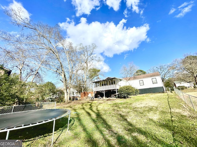 view of yard featuring a sunroom and a trampoline