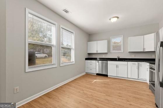 kitchen featuring white cabinetry, sink, light wood-type flooring, and appliances with stainless steel finishes