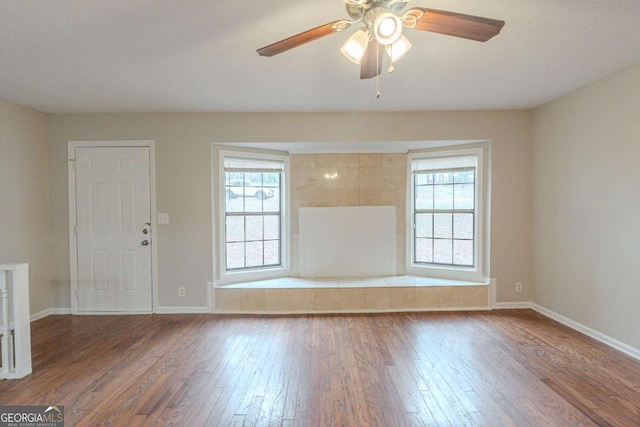 empty room with dark hardwood / wood-style flooring, a wealth of natural light, and ceiling fan